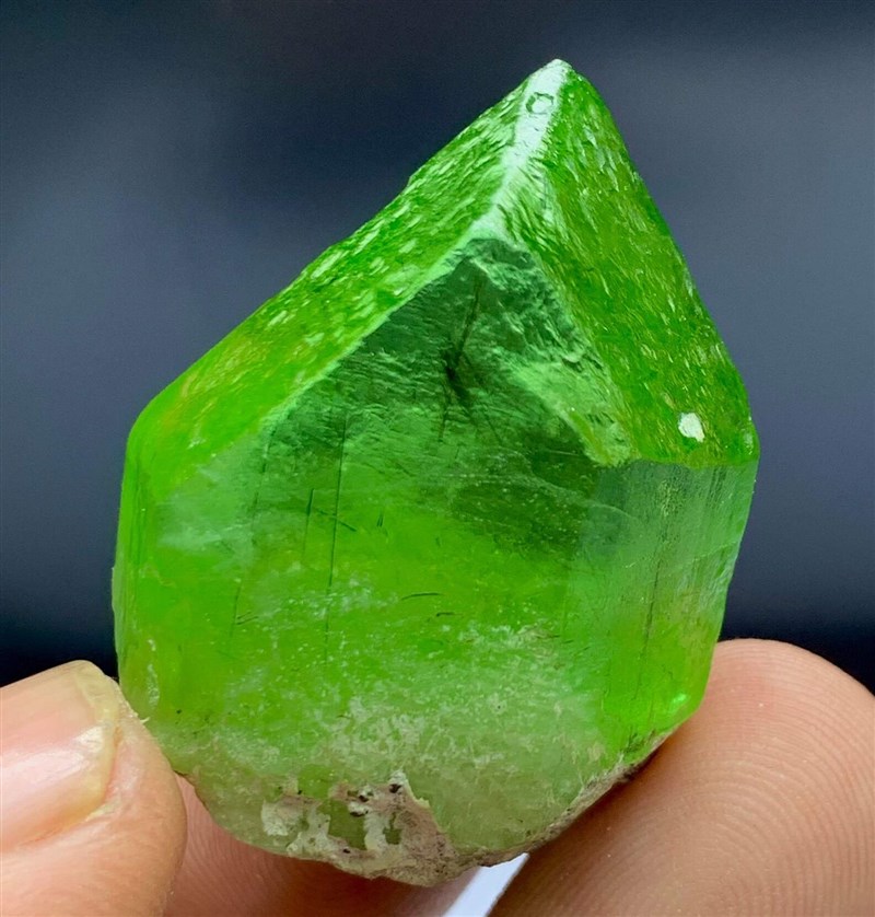 A raw green peridot crystal held to the light